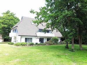 Set amidst a serene and lawn, this charming house features a two-story design with a balcony and a well-manicured yard.