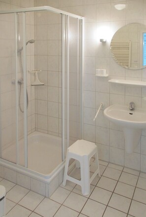 Enjoy a refreshing shower in this sleek bathroom with a glass-enclosed shower area, pedestal sink, and mirror.