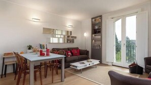 Una sala de estar moderna con comedor, un sofá, una mesa de centro y una estantería.