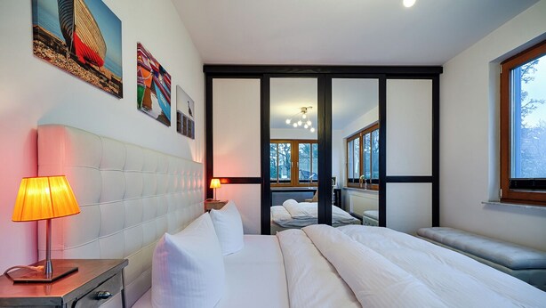 A hotel room with a large bed, bedside tables, a lamp, and artwork on the walls. - Apartment for 2 p. + toddler, central and close to the beach, fireplace, sauna, terrace, WLAN (Prerow)