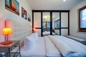 A hotel room with a large bed, bedside tables, a lamp, and artwork on the walls. - Apartment for 2 p. + toddler, central and close to the beach, fireplace, sauna, terrace, WLAN (Prerow)