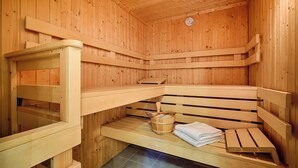 A sauna with wooden benches, a wooden bucket, and a towel. - Apartment for 2 p. + toddler, central and close to the beach, fireplace, sauna, terrace, WLAN (Prerow)