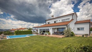 A modern two-story house with a swimming pool, a patio with outdoor furniture, and a well-maintained lawn. - Terra Magica Room with Private Parking (Cavle)