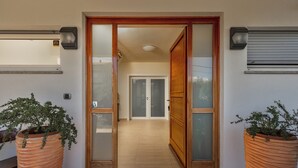A modern entrance with a wooden door, a tiled floor, and two large terracotta planters with plants. - Terra Magica Room with Private Parking (Cavle)