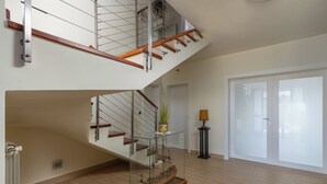A spacious interior with a wooden staircase, a glass display case, and a view of the outside. - Terra Magica Room with Private Parking (Cavle)
