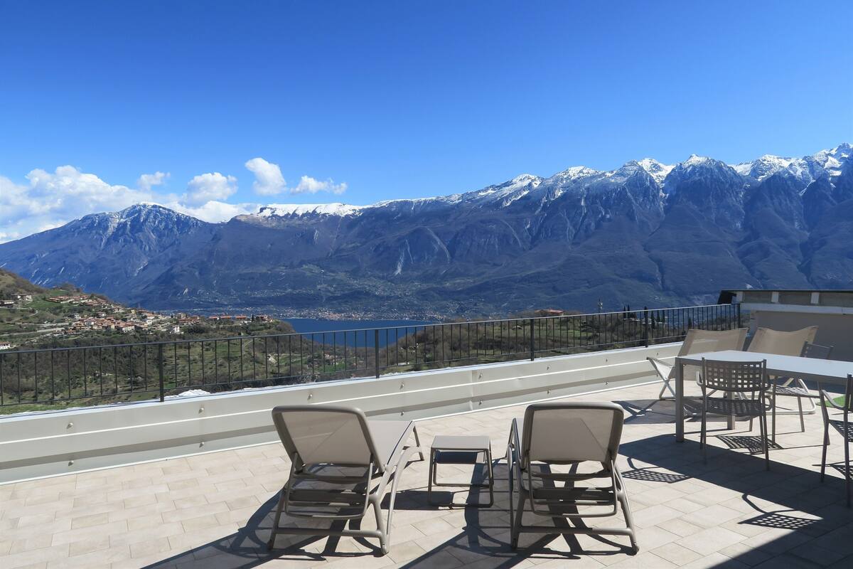 A terrace with outdoor seating and a view of snow-capped mountains.