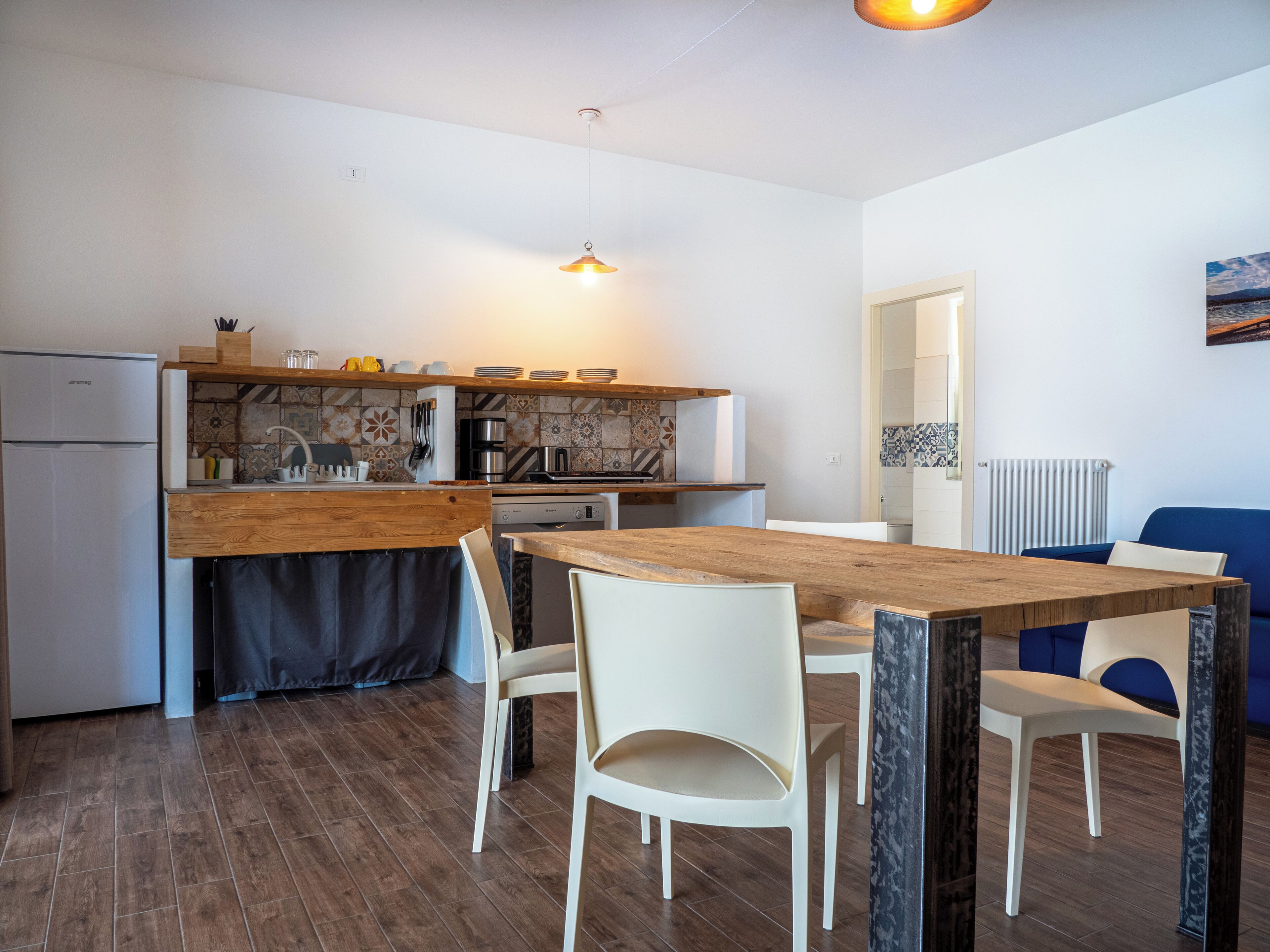 Una cocina moderna con encimeras de madera, horno empotrado y comedor con mesa de madera y sillas blancas.