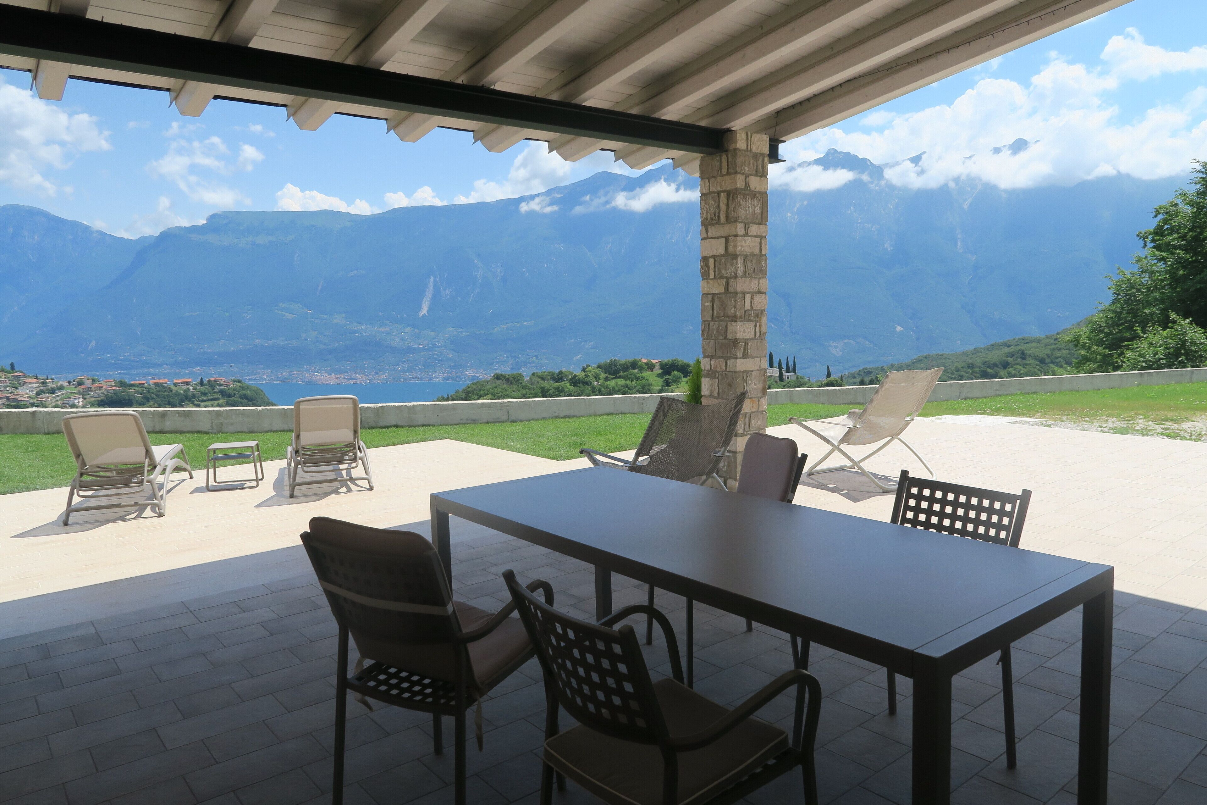 An outdoor patio with a table and chairs, overlooking a mountainous landscape.