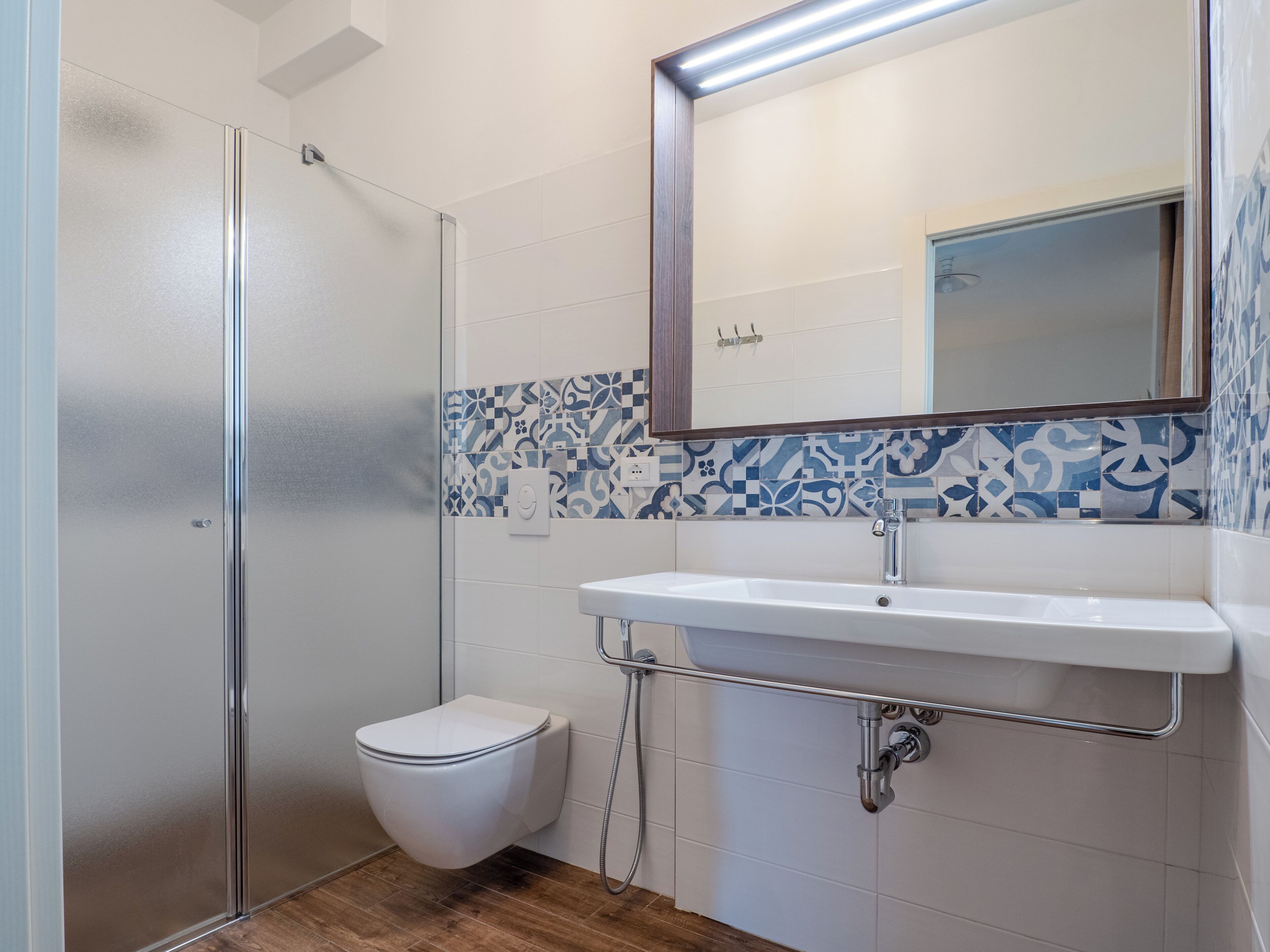 Une salle de bain moderne avec une douche à parois de verre, des toilettes blanches et un lavabo avec un miroir au-dessus.