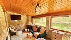 A cozy room with a bed, a sofa, a small table, and a stone wall.
