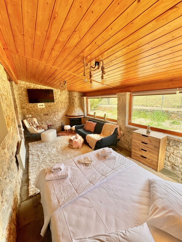Una habitación acogedora con una cama, un sofá, una mesita y una pared de piedra.