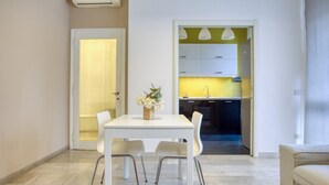 A modern living room with a white dining table and chairs, a beige sofa, and a kitchen visible through an open door. - Easylife - Exclusive Comfort in Porta Romana (Milano)