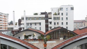 A modern building with a unique curved roof design, large windows, and a central courtyard with potted plants and seating areas. - Easylife - Exclusive Comfort in Porta Romana (Milano)
