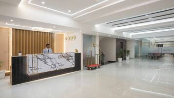 A hotel reception area with a marble reception desk, a gold-framed cart, and a modern interior design.