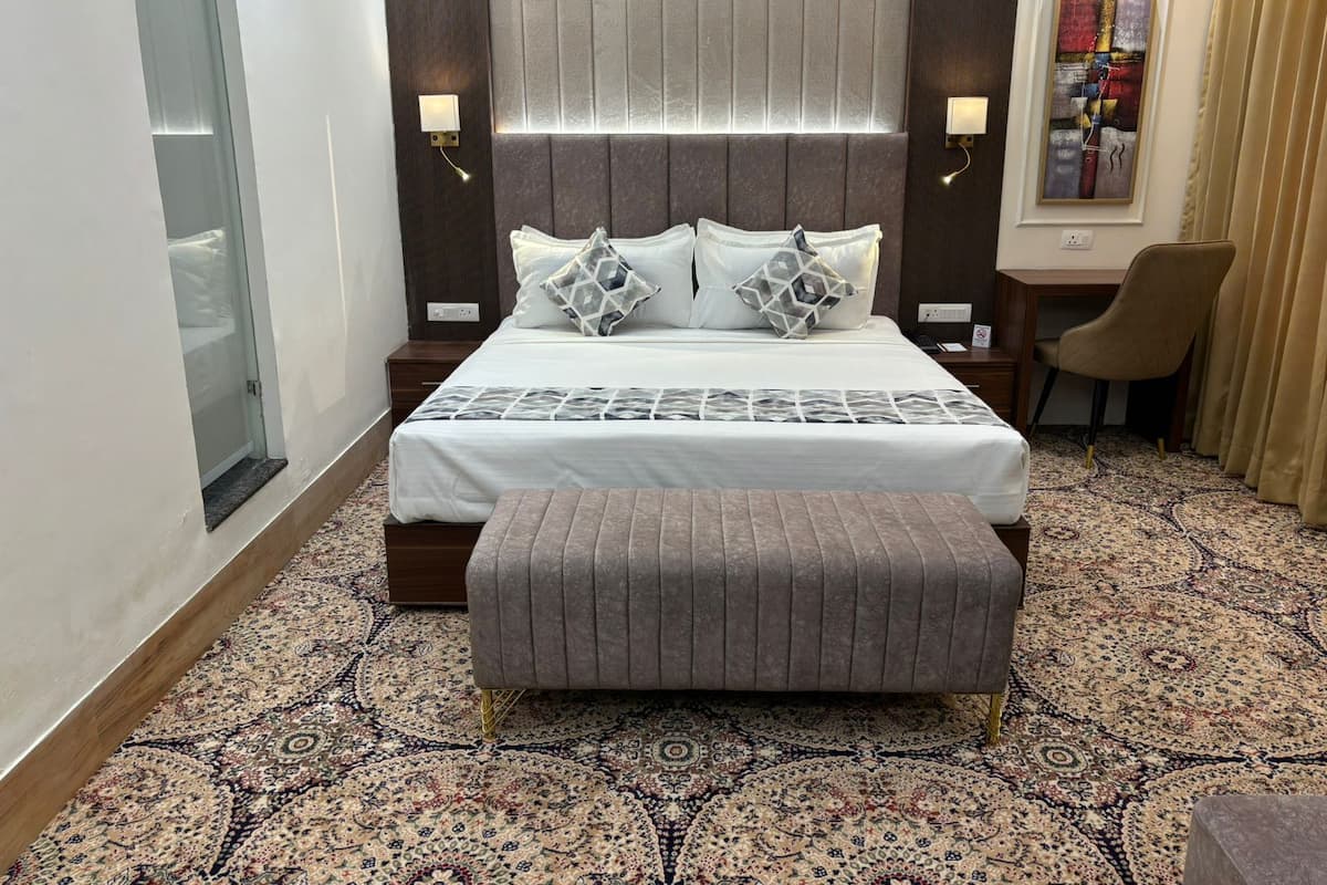 Une chambre d’hôtel avec un grand lit, une table de chevet, une chaise et une moquette à motifs.