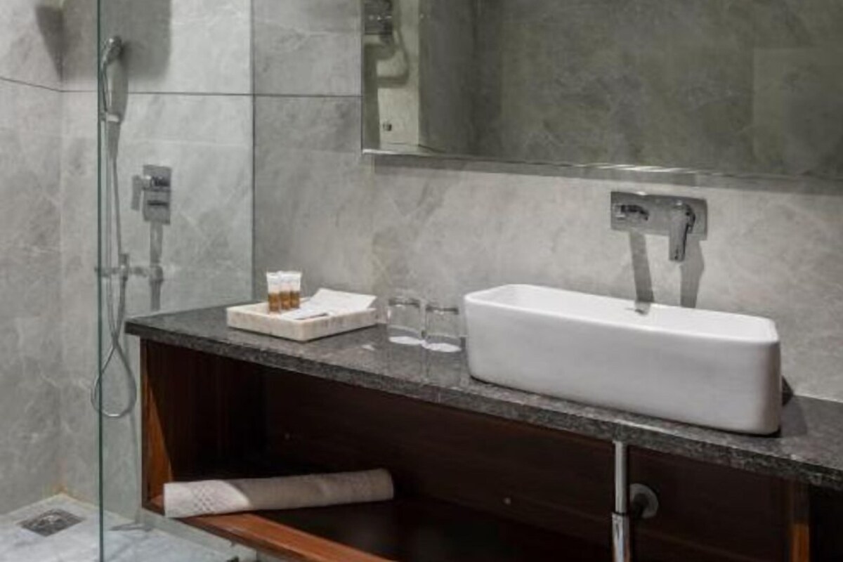 A modern bathroom with a glass shower enclosure, a white sink, and a large mirror.