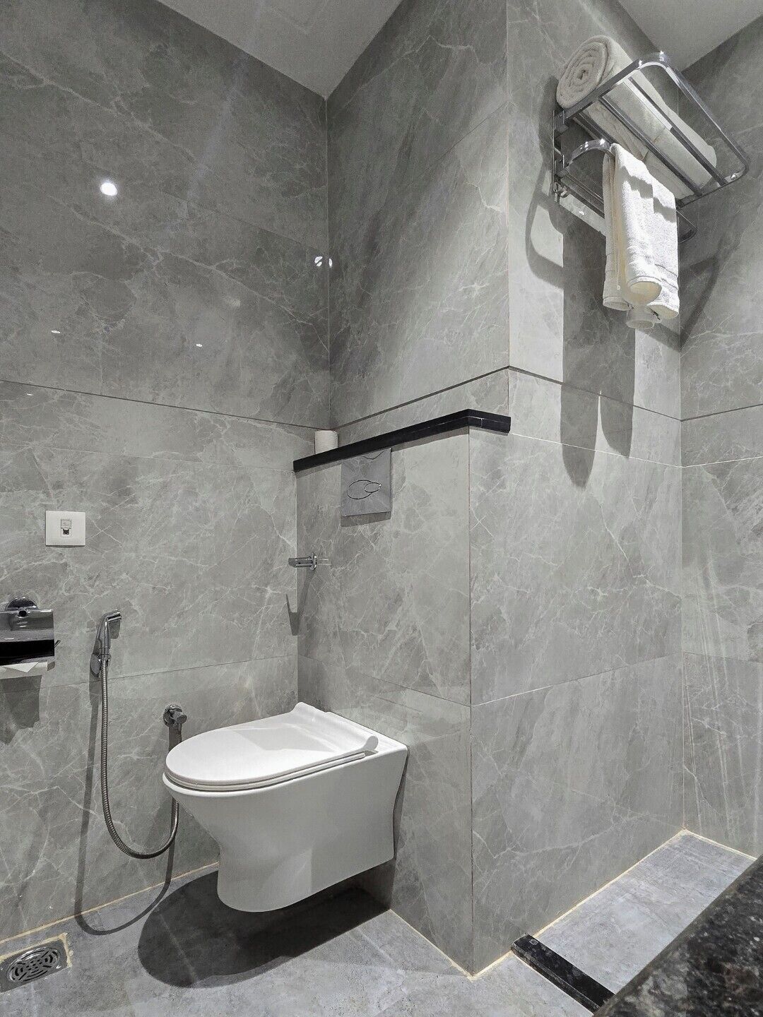 A modern bathroom with a toilet, shower, and towel rack.