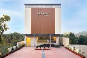 A modern Clark's Inn Suites building with a prominent sign, a glass entrance, and a landscaped courtyard. - Clarks Inn Suites Agra (Agra)