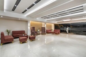 A spacious lobby with a modern design, featuring a red sofa set, a coffee table, and a patterned wall. - Clarks Inn Suites Agra (Agra)