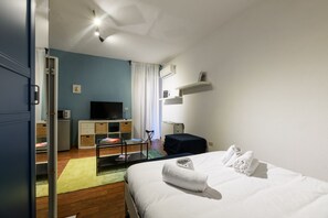Ein Hotelzimmer mit Bett, Schreibtisch mit Stuhl, Fernseher und einer Küchenzeile.