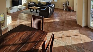 Amplia sala de estar con televisor grande, asientos cómodos y vista al exterior.