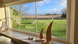 Una habitación con un amplio ventanal que da a un campo verde y un cielo despejado.