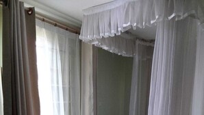 Un dormitorio con cama, cortinas blancas y alfombra negra.