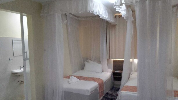 Habitación de hotel con cama, una mesita, un buró, un espejo y un baño con lavamanos e inodoro.
