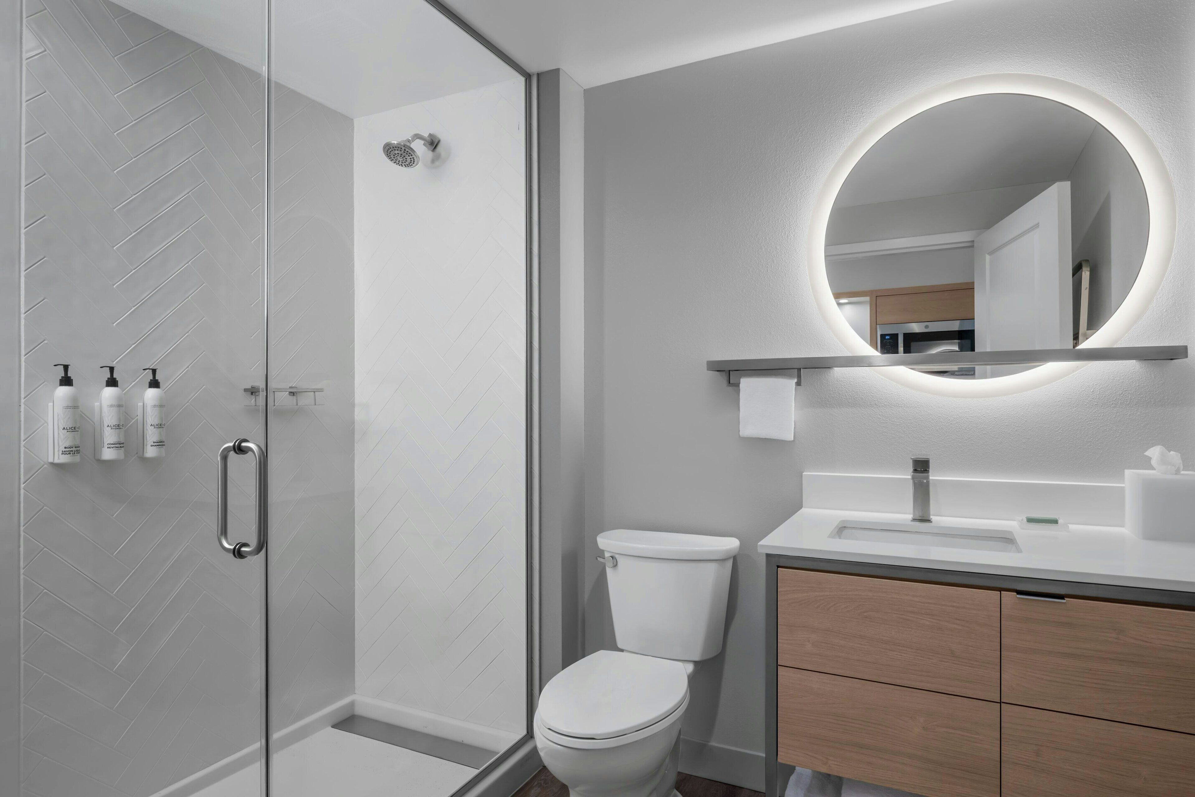 A modern bathroom with a glass shower enclosure, a toilet, and a vanity with a mirror.