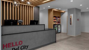 Vastaanottotiski, jossa on kyltti, jossa lukee ”TERVETULOA Del Cityyn”, Lenovo-tietokone, kassakone ja pieni jääkaappi, jossa on tarjolla pientä purtavaa.