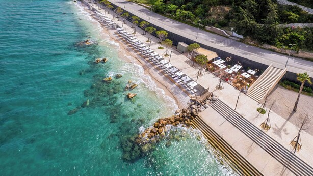 An aerial view of a coastal hotel with a beachside promenade, outdoor seating areas, and a clear view of the turquoise sea. - Hotel Vlora Priam, Affiliated By Meliá (Vlorë)
