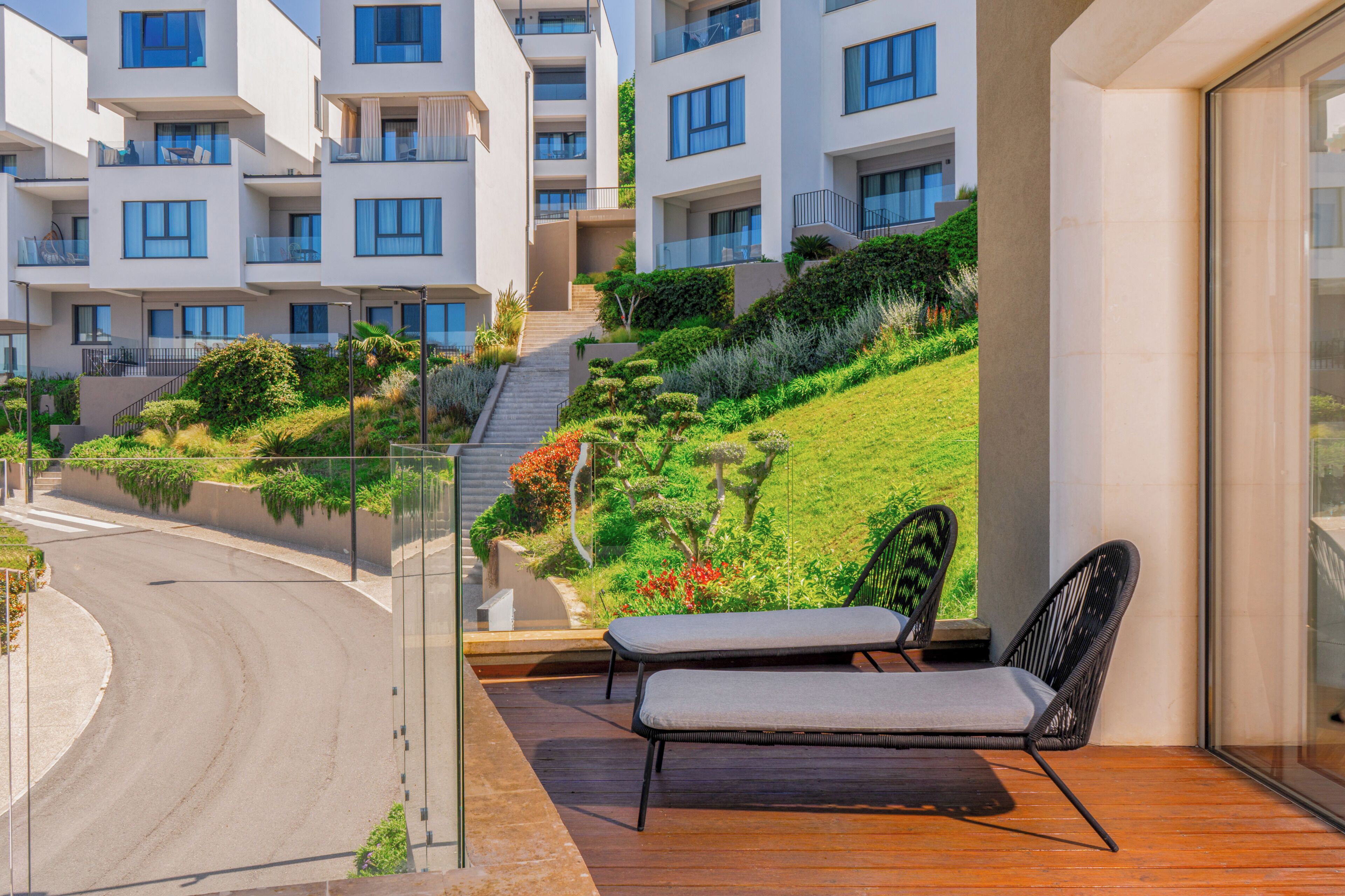 Un balcón con vistas a una zona residencial, una calle y áreas verdes.