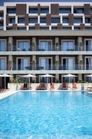 Una piscina al aire libre, sombrillas, sillones reclinables de piscina
