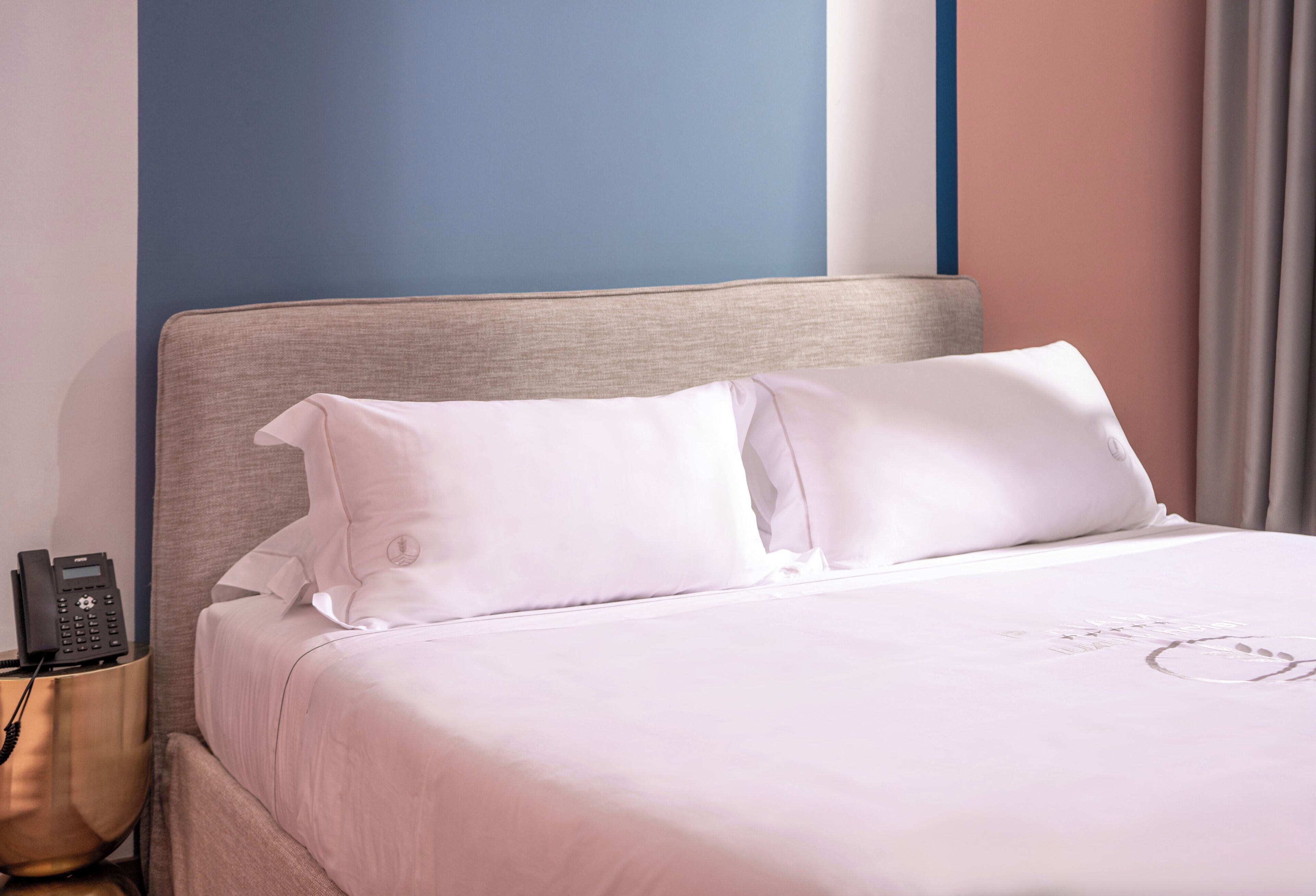 Une chambre d’hôtel avec un lit, un téléphone sur la table de chevet et une petite table de nuit.