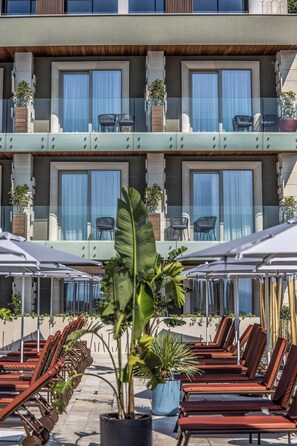 A hotel with a rooftop lounge area featuring sun loungers, potted plants, and umbrellas. - Hotel Vlora Priam, Affiliated By Meliá (Vlorë)