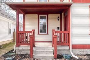 Una casa con un porche rojo, una puerta principal y escalones que conducen a la entrada.