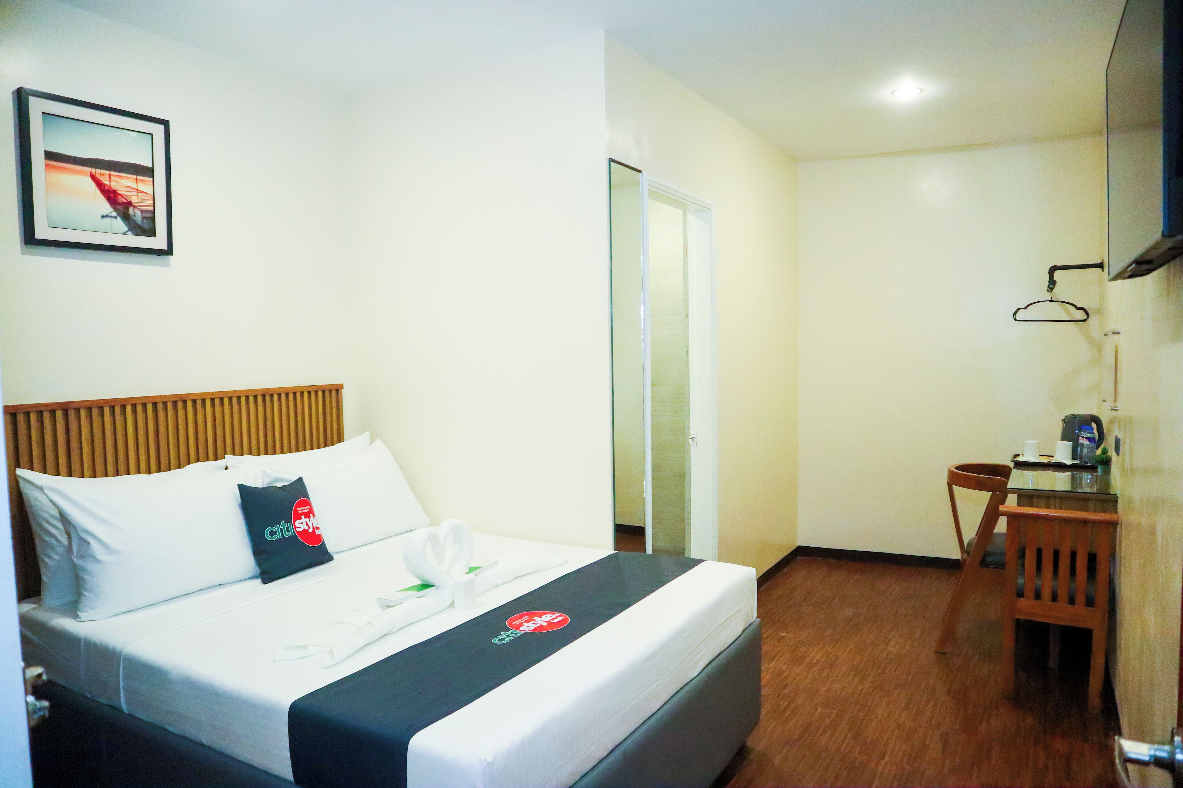 Ein Hotelzimmer mit Bett, Holz-Kopfteil, Esstisch mit Stühlen und einer kleinen Küchenzeile.