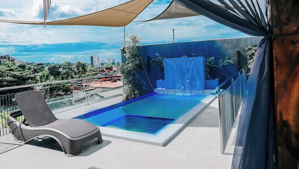 A rooftop pool area with a lounge chair, a water feature, and a view of the cityscape. - CITISTYLE INN INC. (Davao)