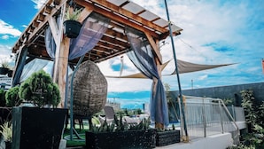 A wooden pergola with a hanging basket and potted plants, overlooking a cityscape. - CITISTYLE INN INC. (Davao)