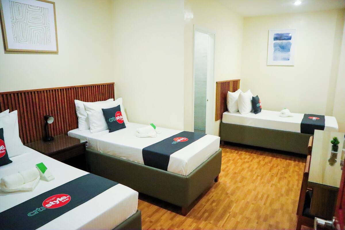 Quarto de hotel com duas camas, soalho em madeira e espelho na parede.