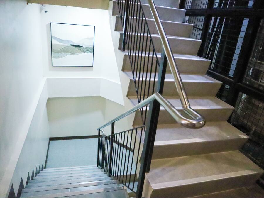 A staircase with metal railings and a handrail, leading to a lower floor.
