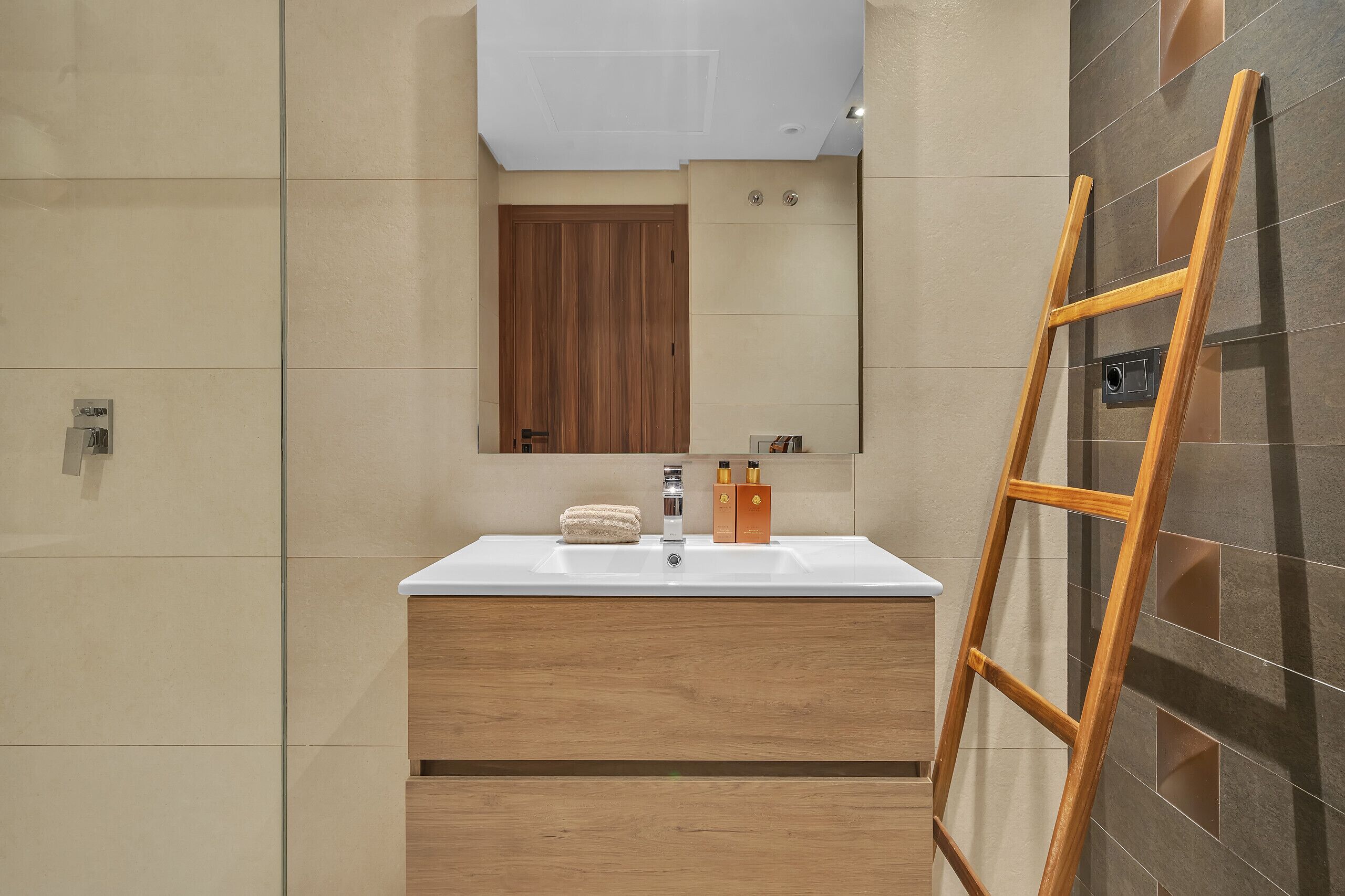 A bathroom with a wooden vanity, a white sink, and a mirror above it.