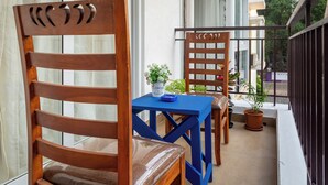 A balcony with two wooden chairs, a blue table, and potted plants.