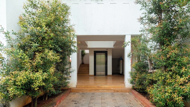 A building entrance with a brick pathway leading to a staircase and a door.