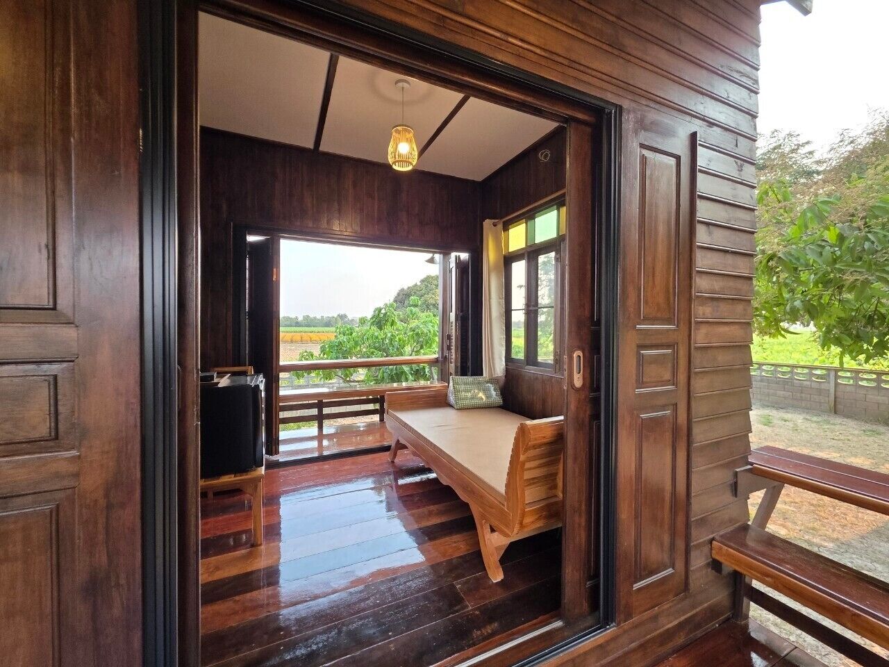 A wooden room with a bench, a small table, and a view of greenery outside.