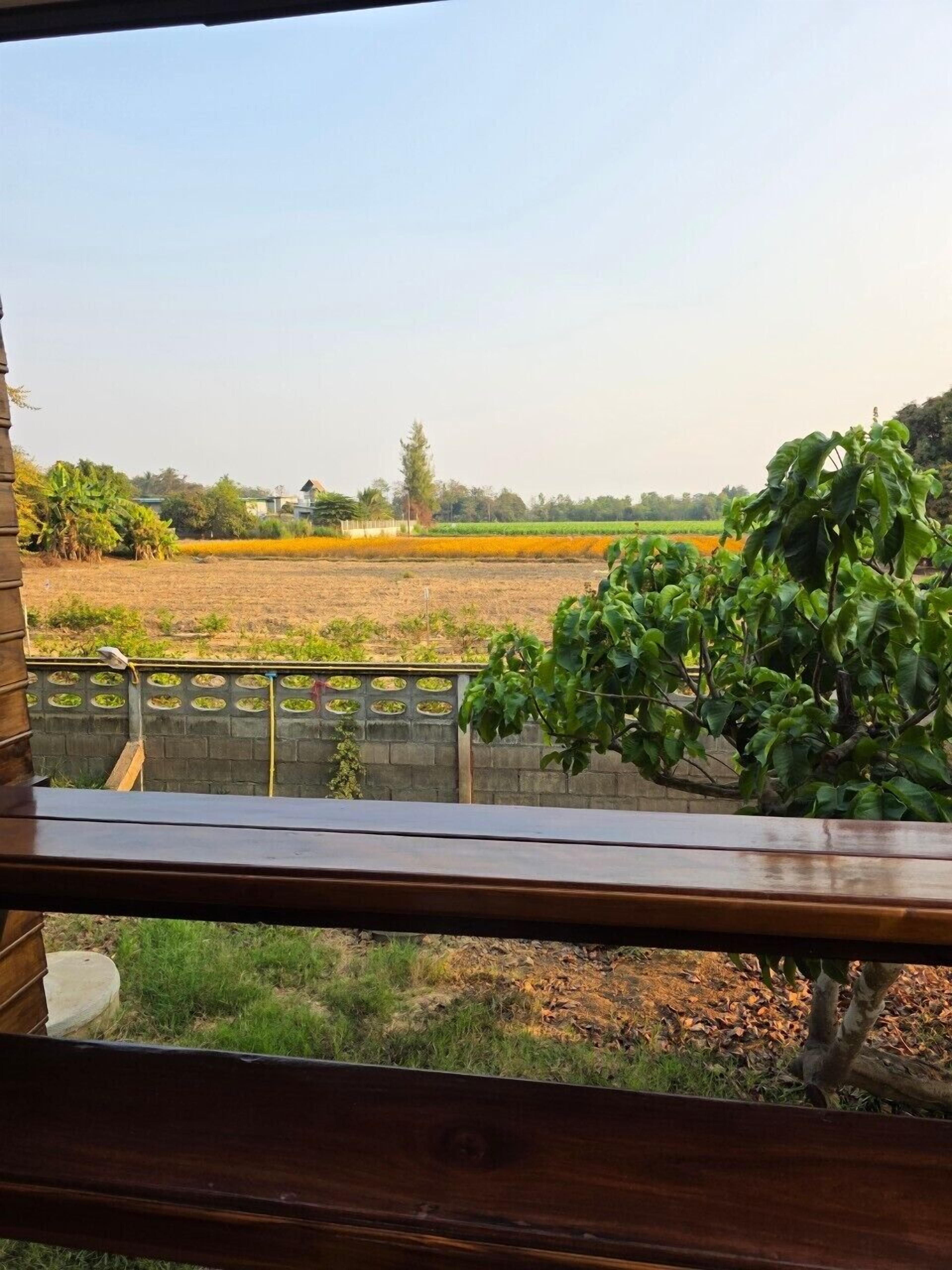 A view from a balcony overlooking a rural landscape with fields and trees.