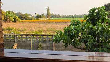 A view from a balcony overlooking a rural landscape with fields and trees.