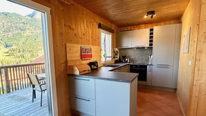 Un interior de madera con cocina y comedor, que cuenta con un ventanal grande y un balcón.
