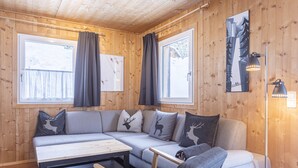 Interior acogedor de una cabaña con un sofá modular, una mesita y una lámpara.