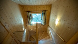 Ein Holzinnenraum mit einer Treppe, die zu einem Fenster mit Karottenvorhängen führt.